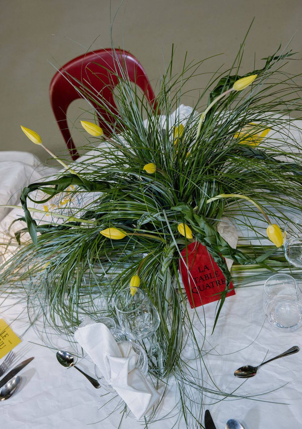 Fresh pine branches with yellow decorative elements and red accents arranged on a white surface create a festive display.