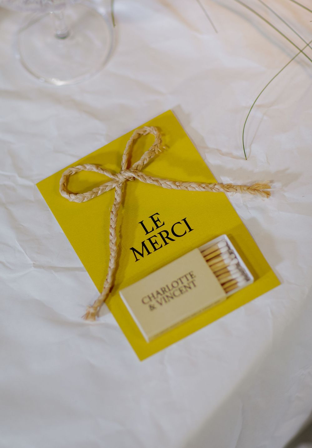 Yellow thank you cards with twine bows and matchboxes arranged on white fabric for event favors.