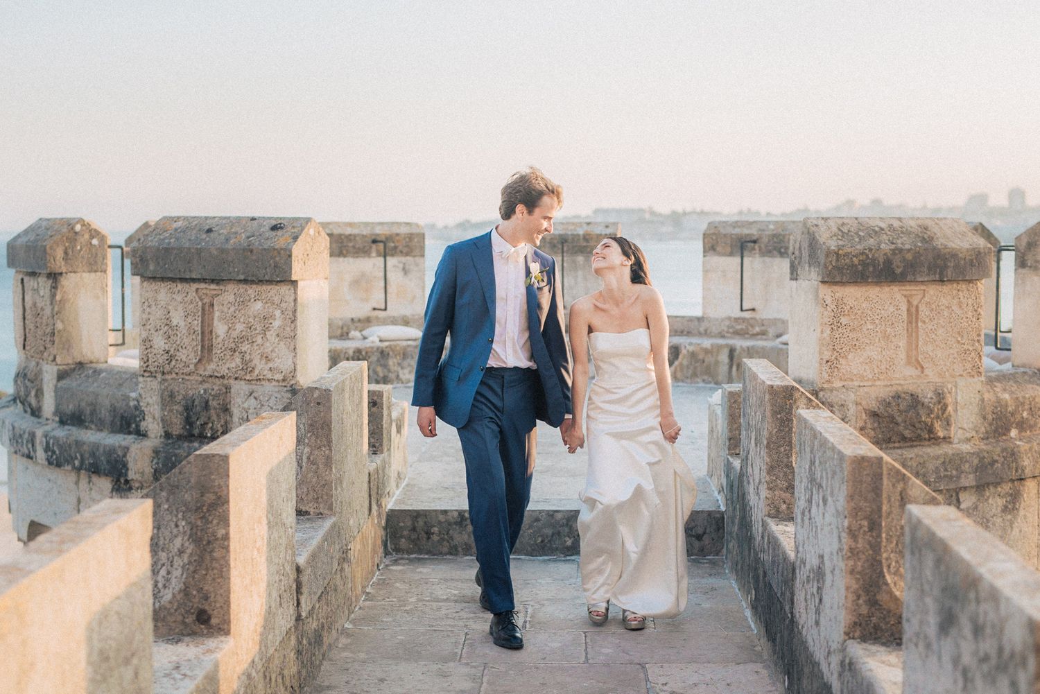 candid portrait of bride & groom in front of the sea at forte da cruz—captured by a destination wedding photographer in Portugal.