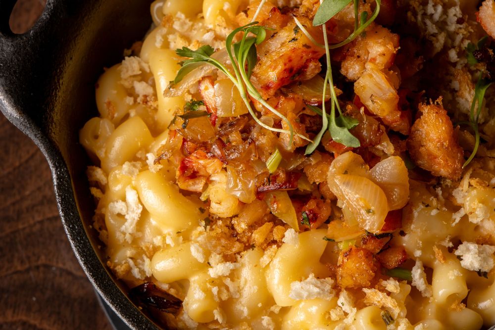 Creamy mac and cheese topped with crispy bacon and microgreens in dark bowl. By NJ Photographer Andrew Fein
