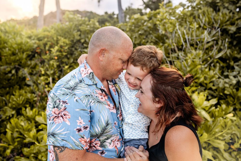 Family sharing a tender moment outdoors in tropical garden setting.
