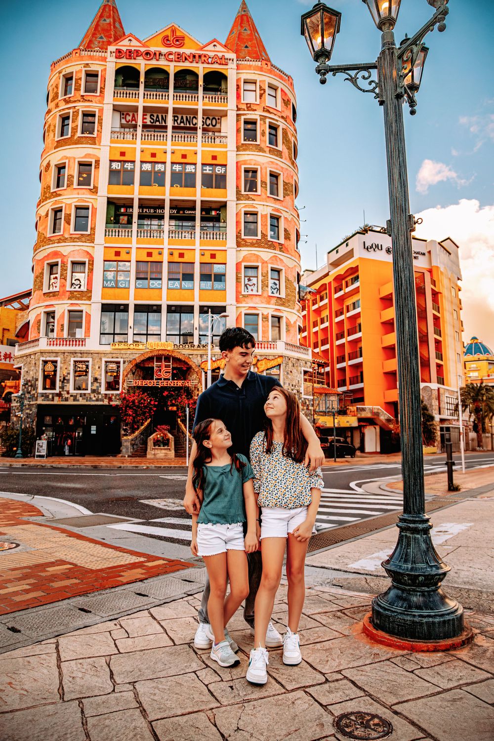 People exploring a vibrant historic district with orange architecture and ornate street lamps in the golden hour.