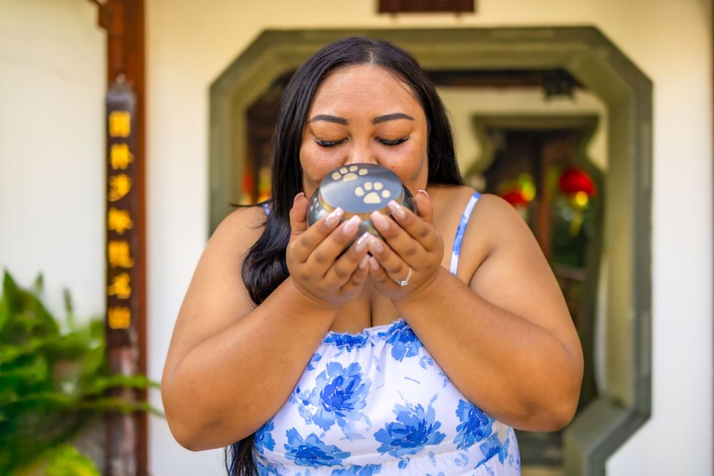 Person in blue and white dress holding something close to their face with closed eyes.