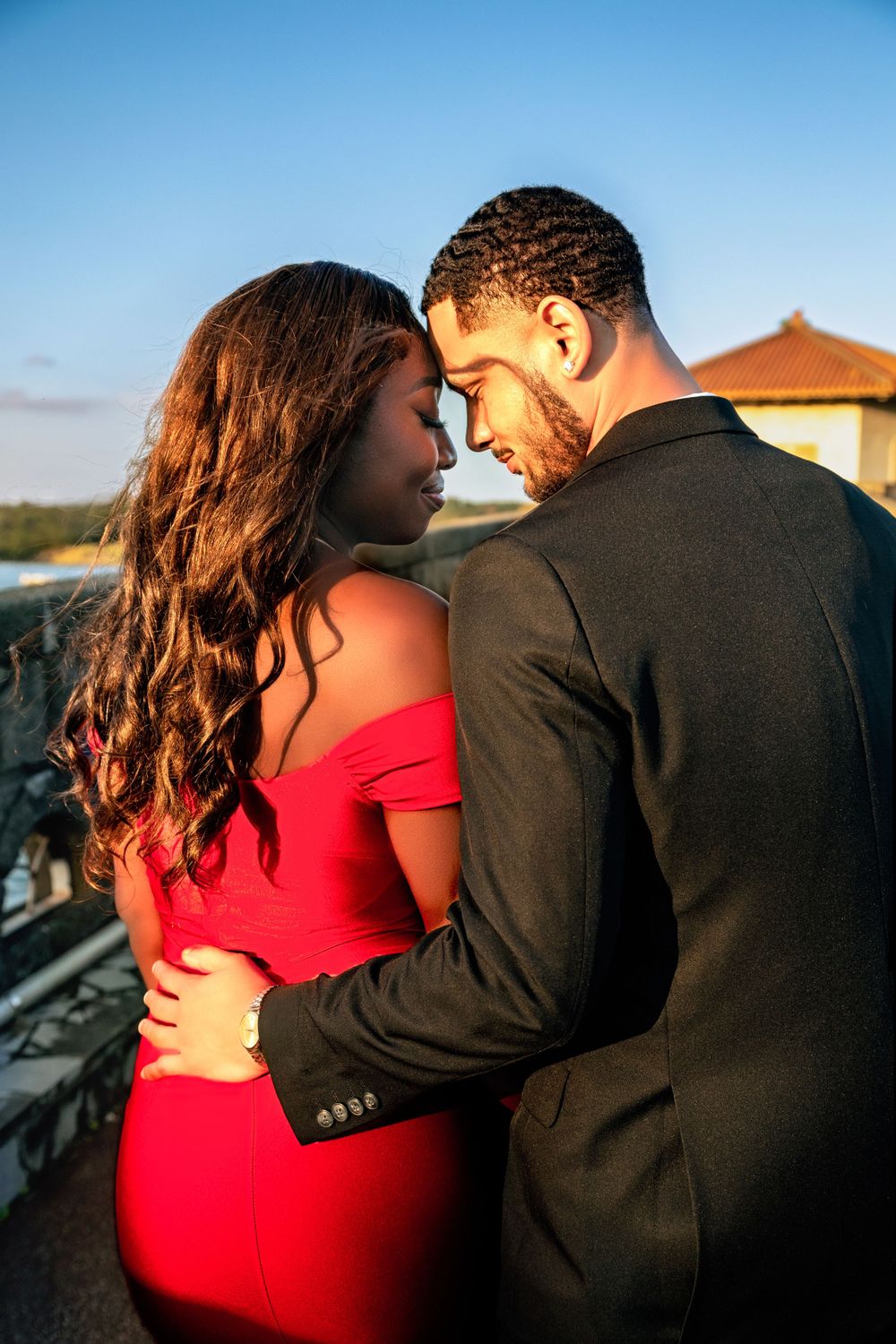 Romantic couple in formal attire sharing an intimate moment at sunset.