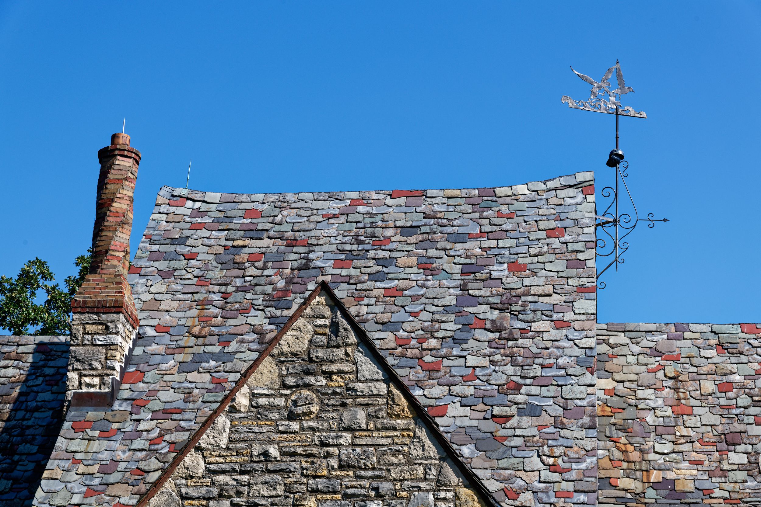 Panoramic view of old brick rooftops with chimneys against a bright blue sky.
