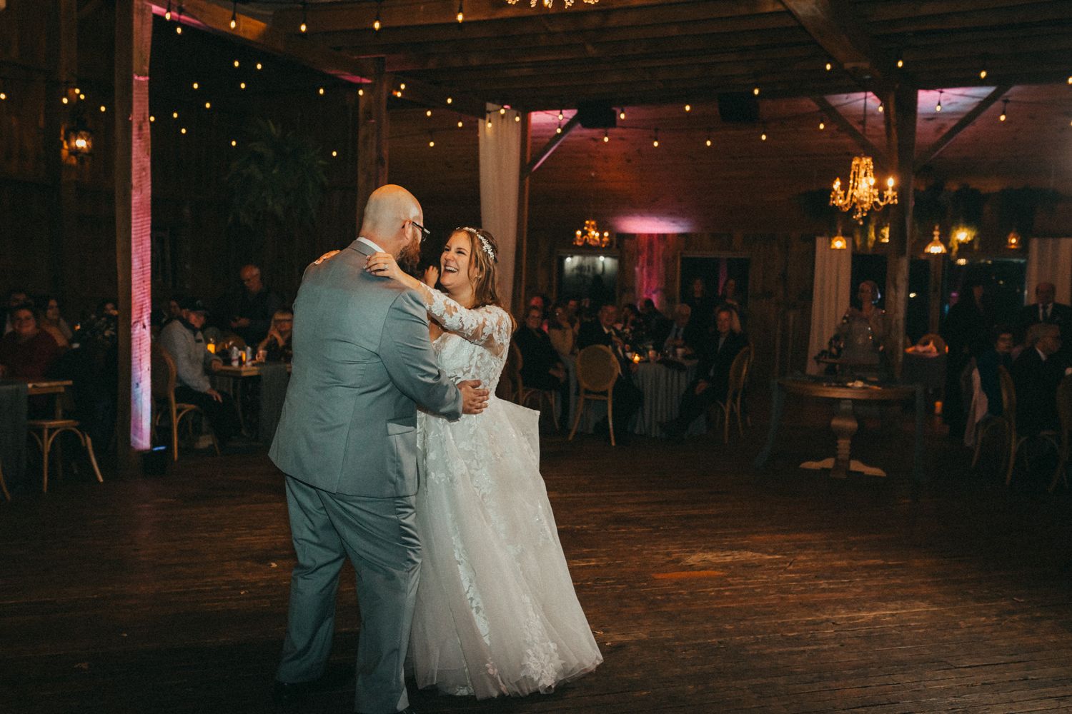 Wedding couple dancing together on a dark wooden floor under ambient lighting at their reception. Pittsburgh wedding Photographer