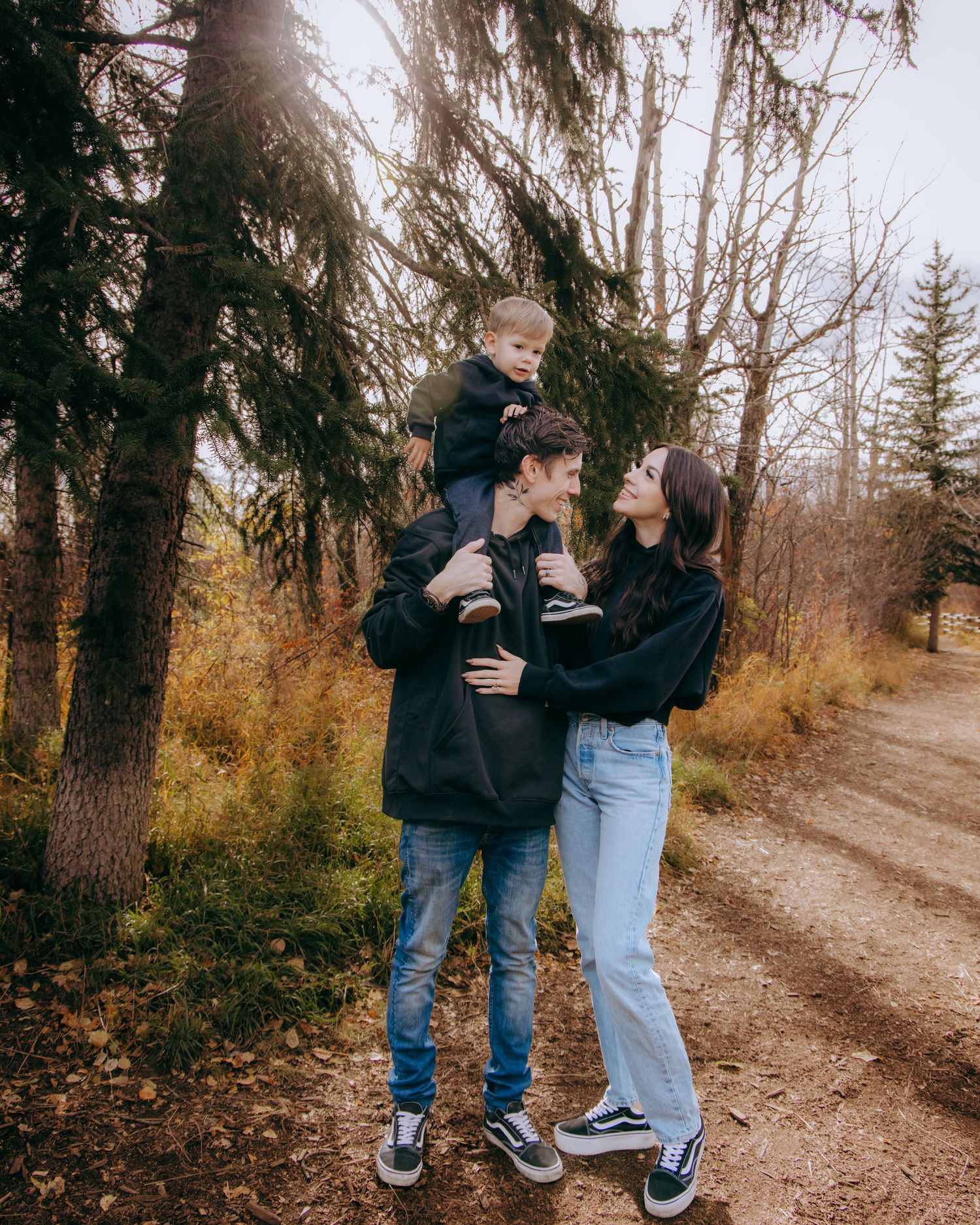 People in casual denim outfits embracing on a wooded autumn trail.
