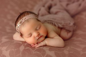 This is a lovely and serene newborn photo. The peaceful sleeping pose, combined with the soft, neutral tones, creates a warm and cozy feel.