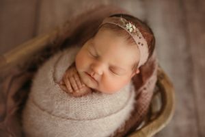 This is a lovely and serene newborn photo. The peaceful sleeping pose, combined with the soft, neutral tones, creates a warm and cozy feel.