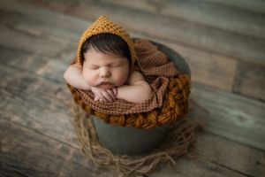 Rustic wooden backdrop with woven basket for newborn photography.
