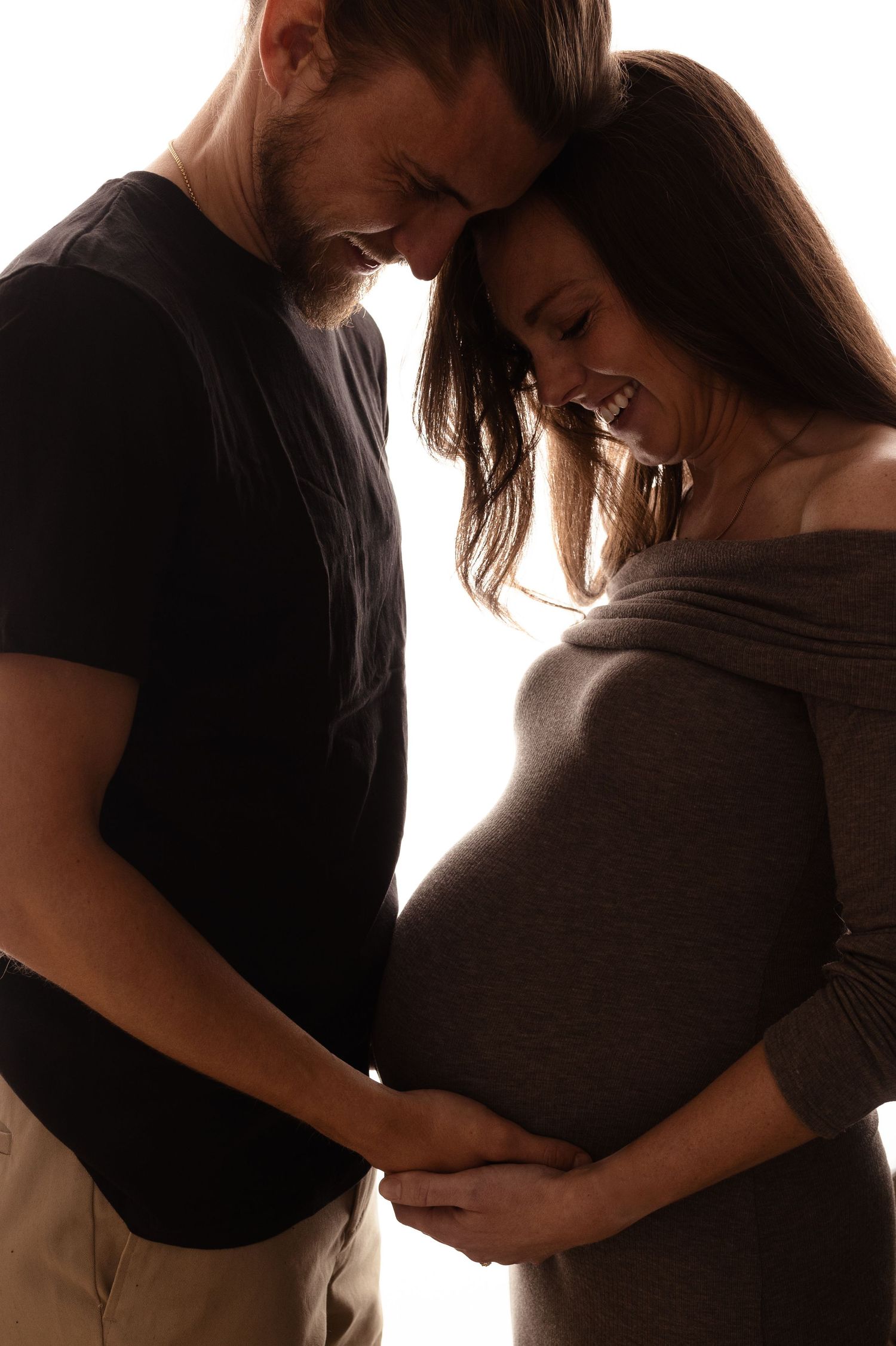 Charlottesville photographer, maternity, newborn, family, baby, pregnant couple in intimate pose, gray clothing, and smiling at belly