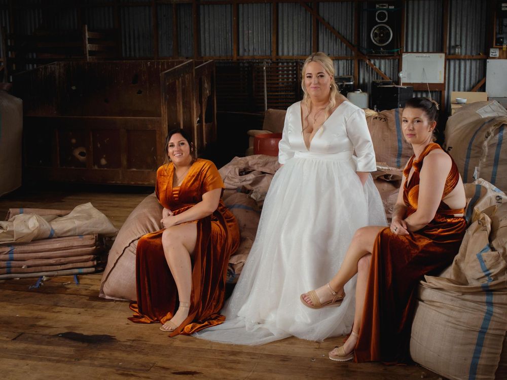 Three people in formal attire sit together in a rustic setting with wooden walls and industrial decor.