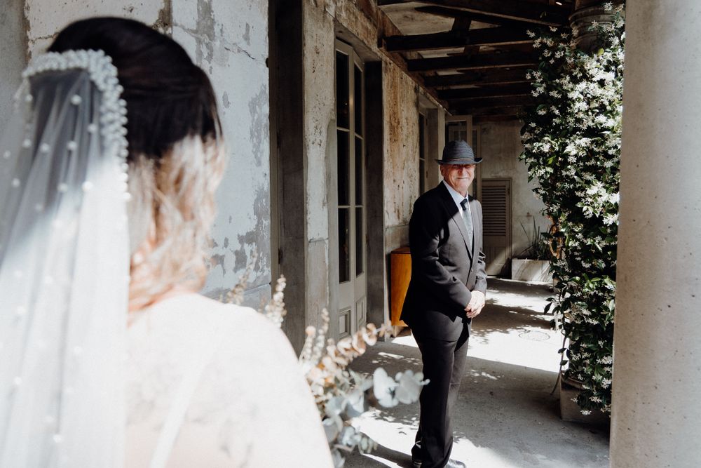 Bride in white veil looks towardher father before their First Look, captured by Apertured Media Auckland Wedding Photographer.
