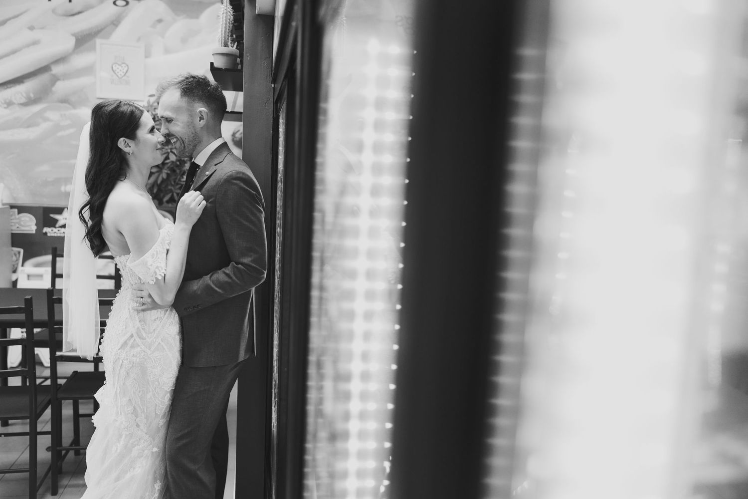 Black and white intimate wedding portrait against brick wall exterior.