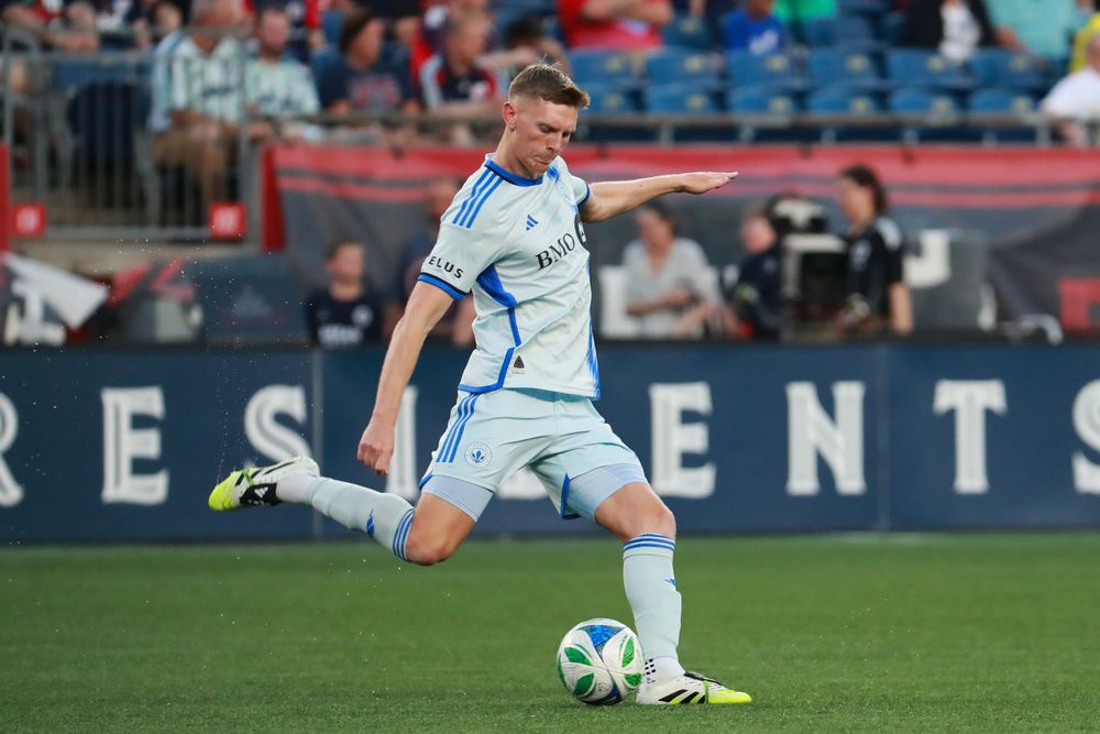 Soccer players in action on field during professional match under stadium lights.