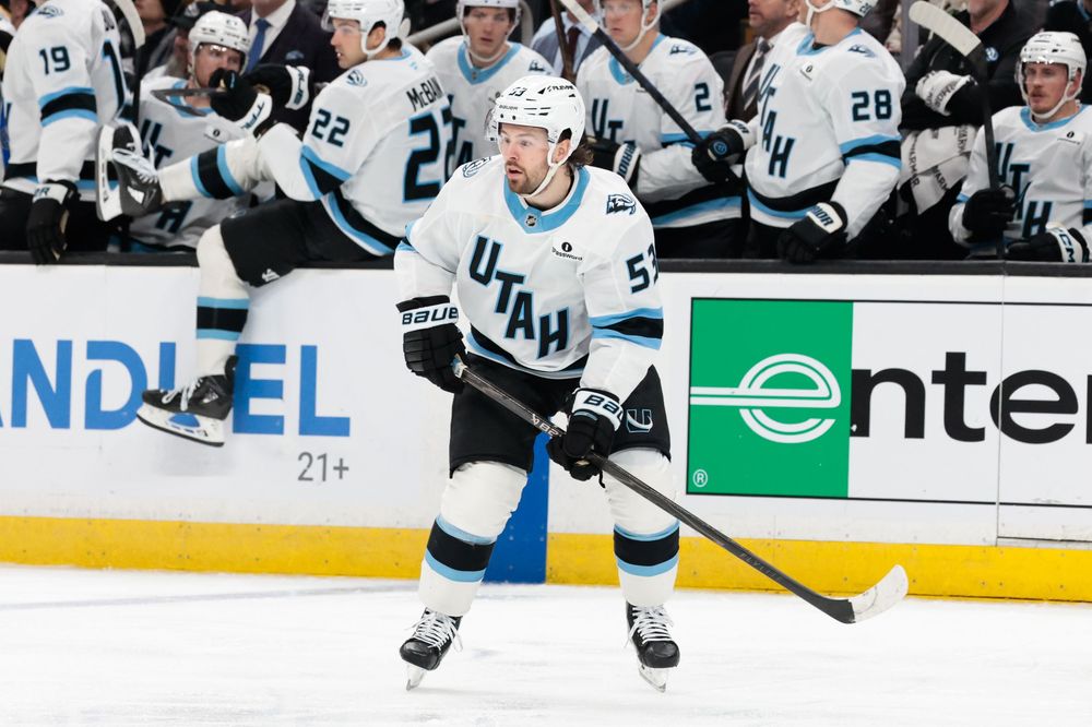 NHL players in white jerseys skate on ice during competitive gameplay.