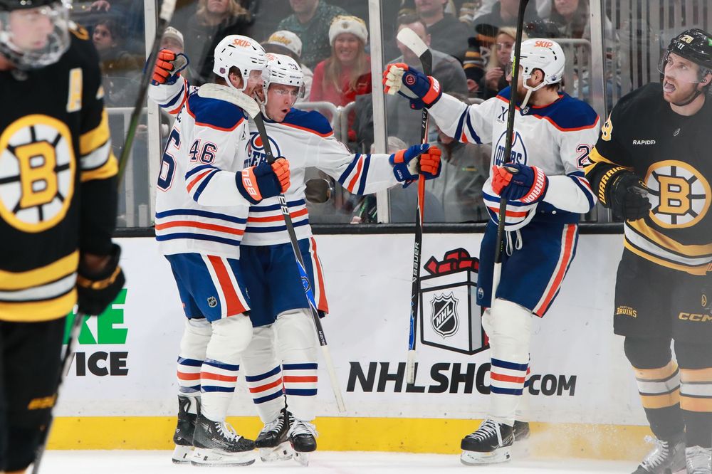 NHL players from the Oilers and Bruins face off during an intense hockey game.