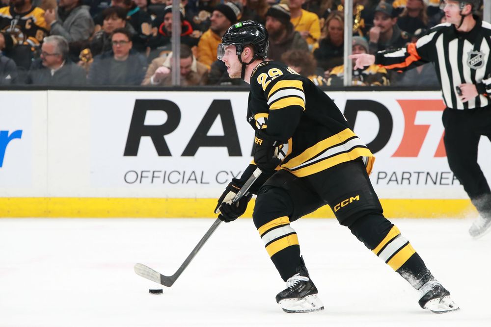 Hockey players from Boston Bruins and opposing team compete during intense match.
