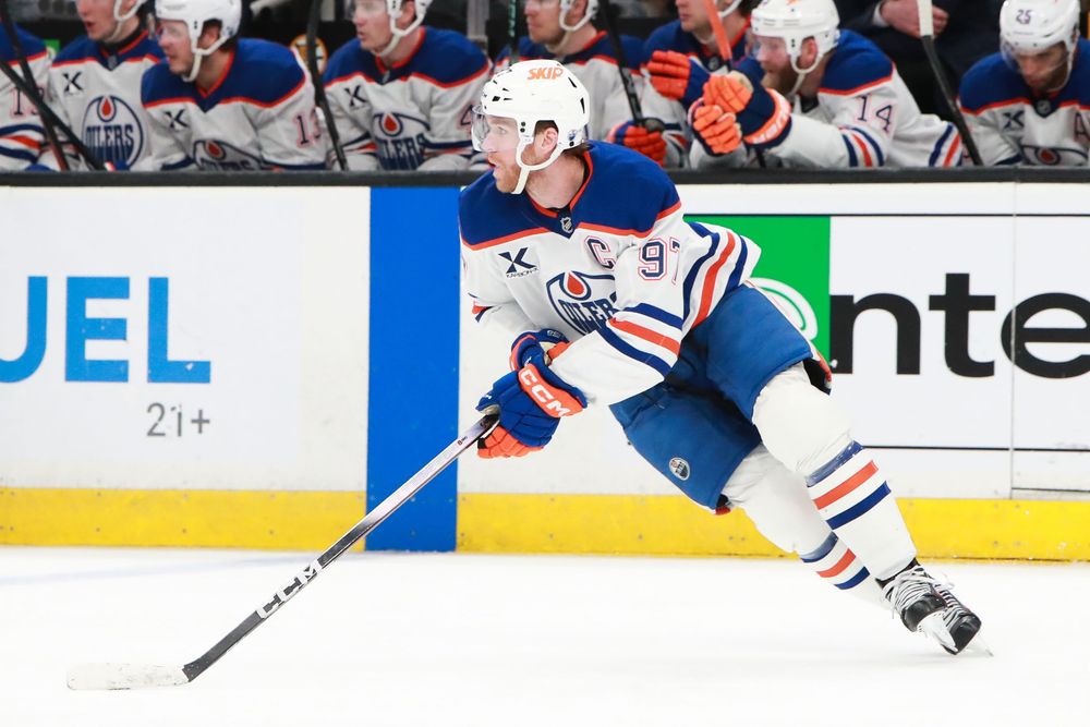 NHL players battle for the puck along the boards during an Oilers versus Bruins game.