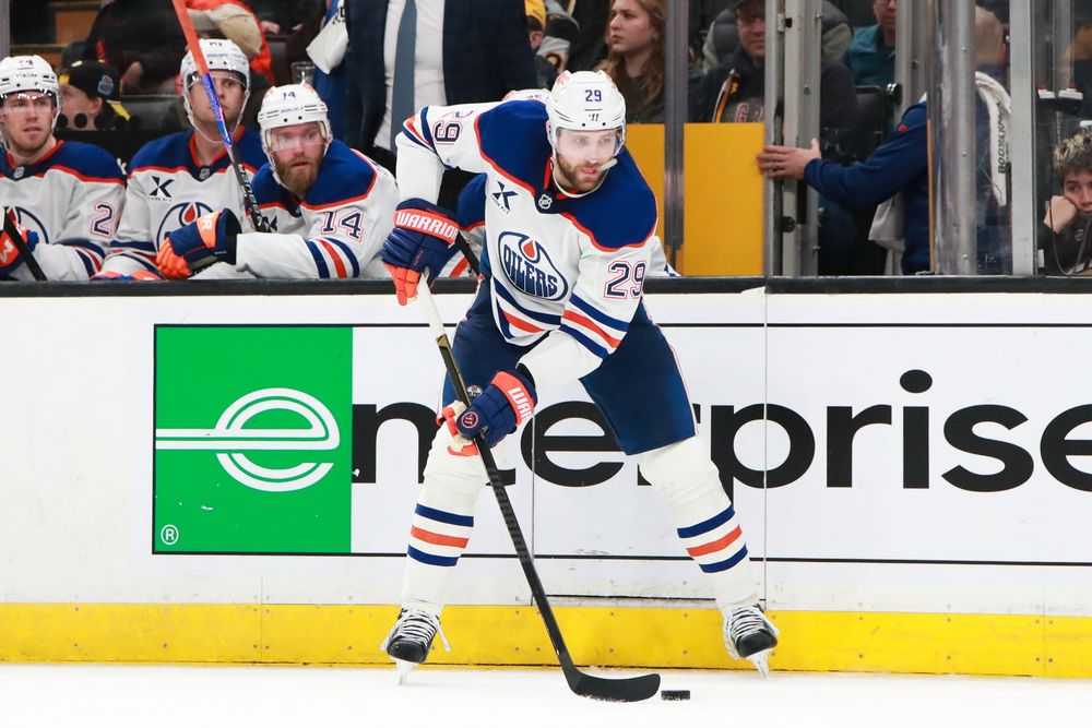 Hockey players from the Edmonton Oilers and Boston Bruins battle for the puck during an NHL game.