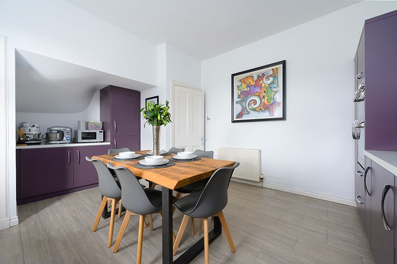 Modern apartment interior with white walls, purple accent wall, hardwood floors and contemporary dining furniture.