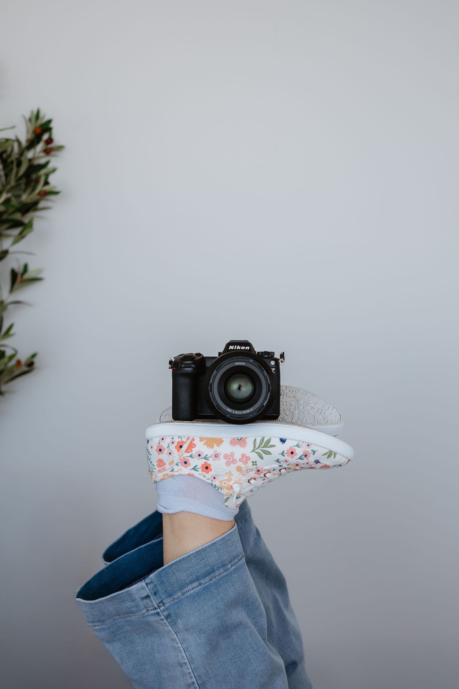 Professional camera and floral patterned fabric detail against light background.
