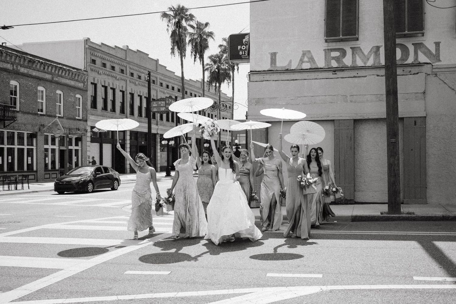 Black and white photo showing vintage storefronts and pedestrians walking along a city sidewalk in the 1950s.