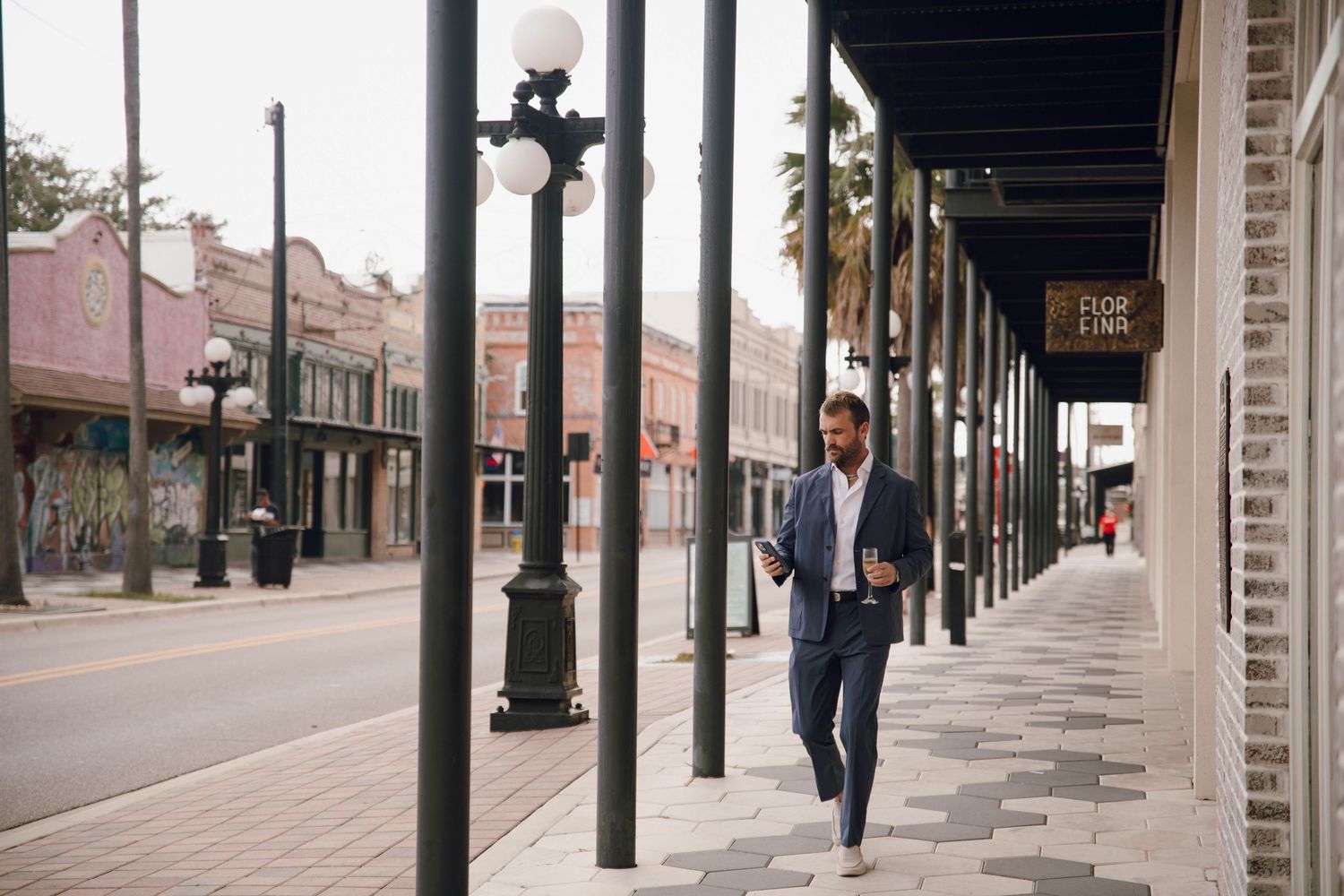 Wedding party walks along a covered brick sidewalk with classic architecture and columns.