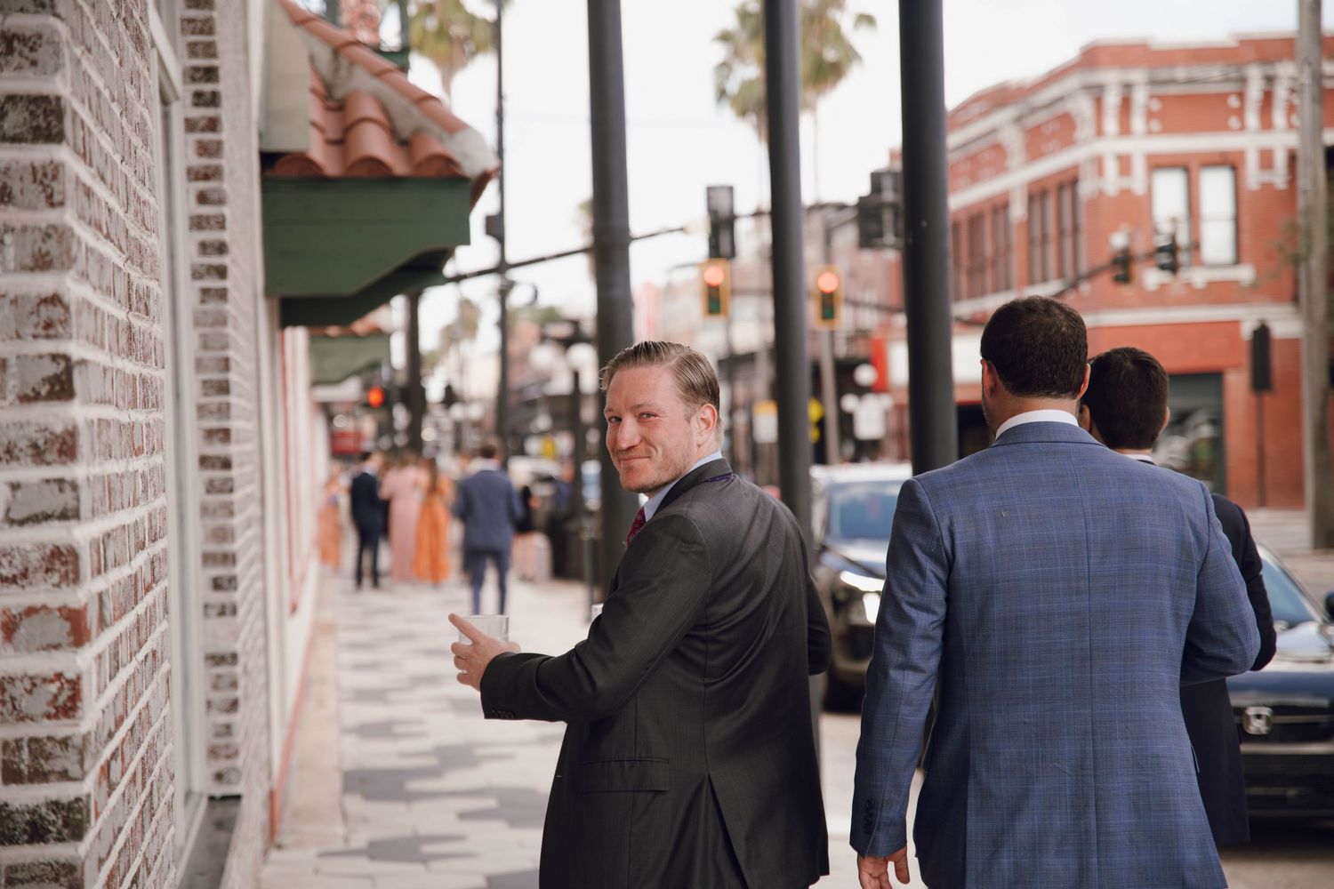 Guests walk under a covered brick colonnade before a wedding ceremony.