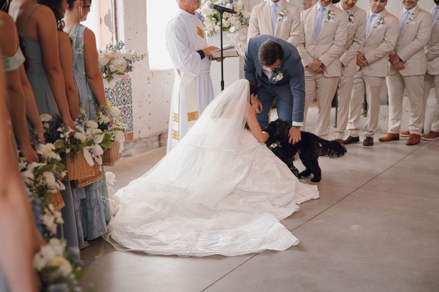 Wedding ceremony setup with white floral arrangements and chairs in an industrial space.