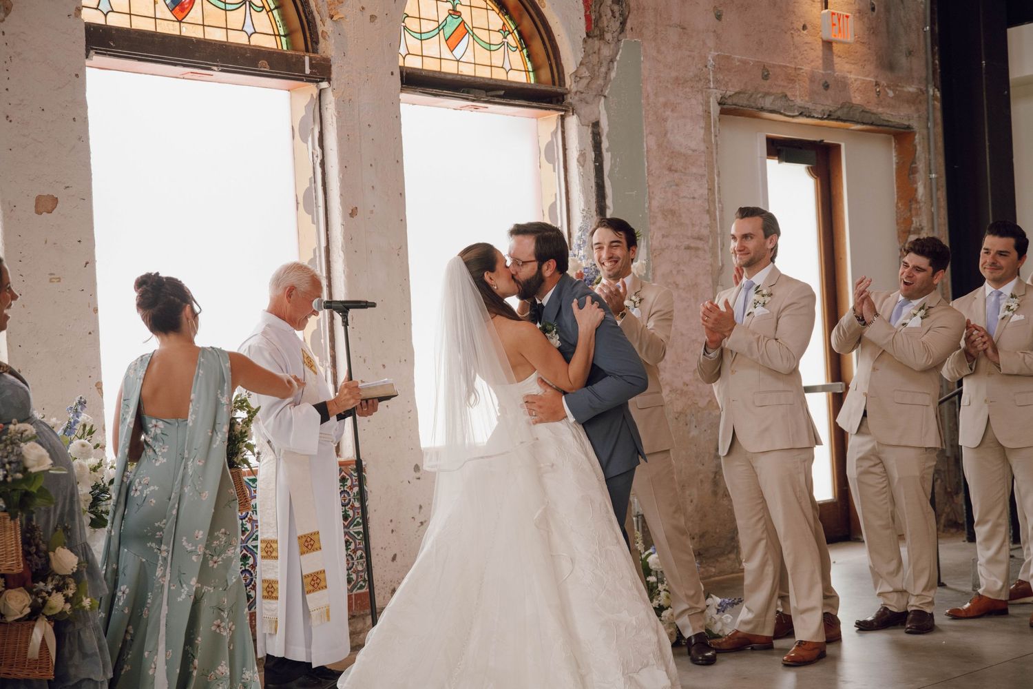 Wedding ceremony in progress at a rustic brick venue with stained glass windows.