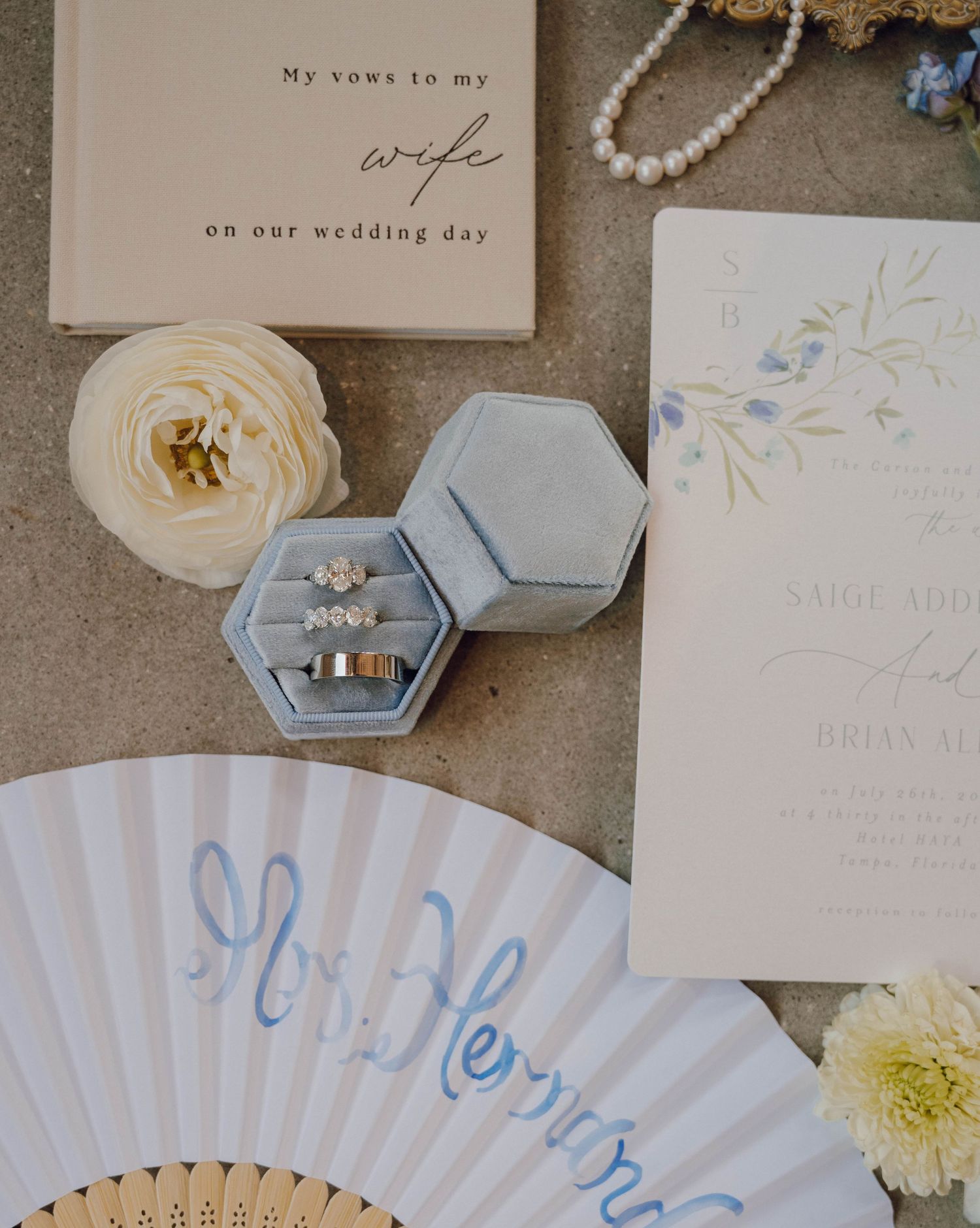Elegant wedding details featuring paper fans, rings, floral invitations, and hexagonal ring boxes in soft pastel colors.