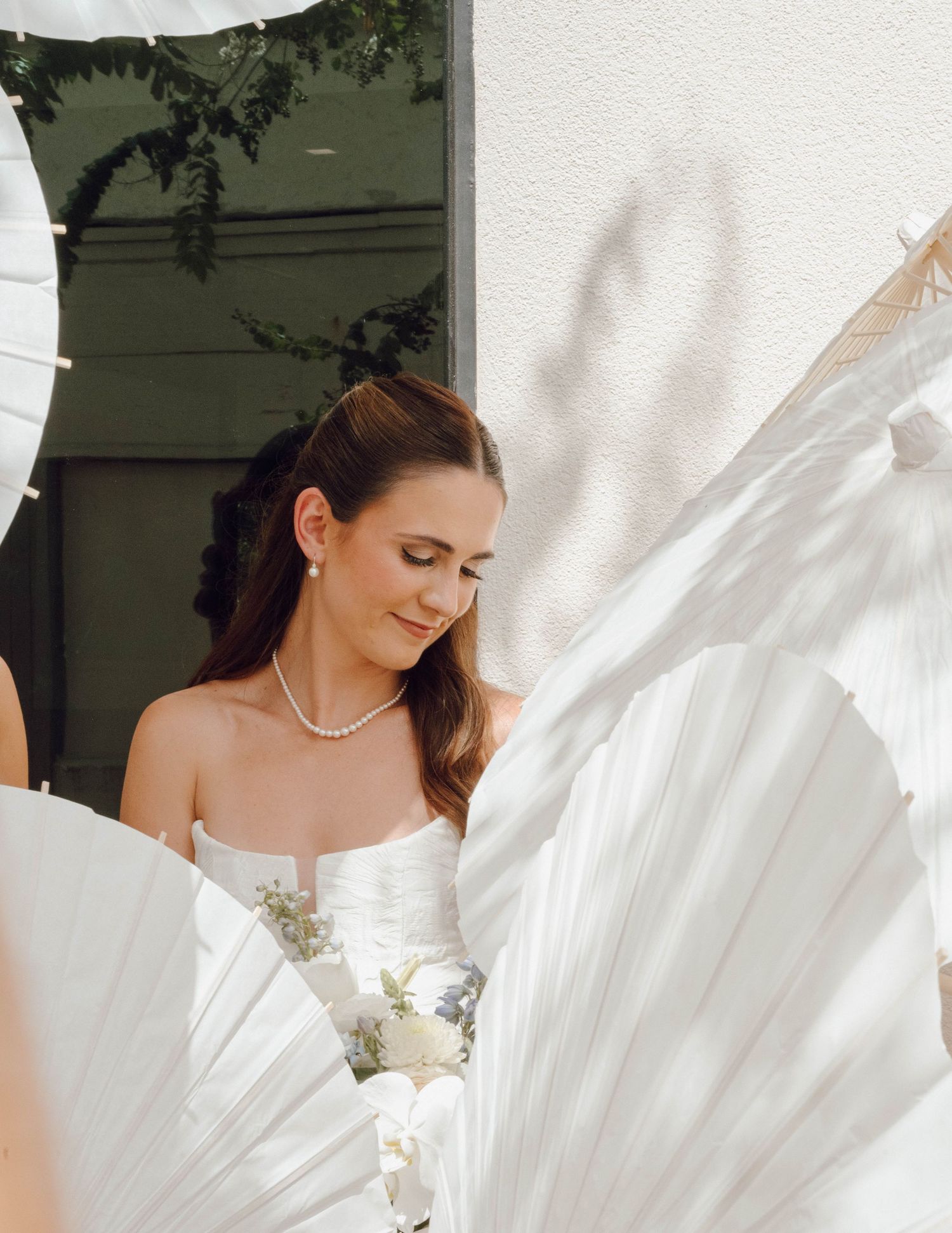 A flowing white wedding dress billows elegantly in the breeze against a soft green background.