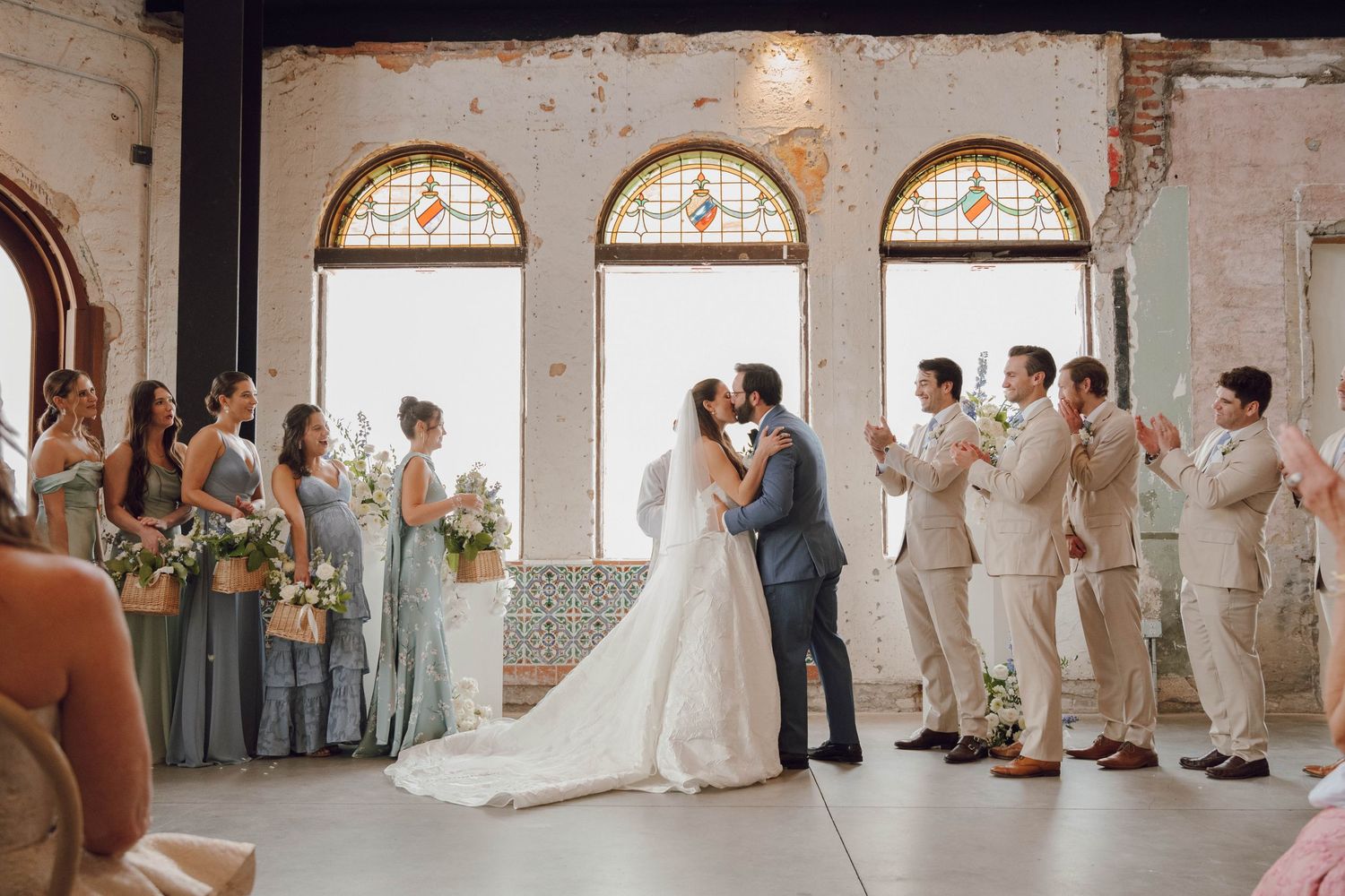 Wide angle view of a wedding celebration in a historic brick building with stained glass windows.