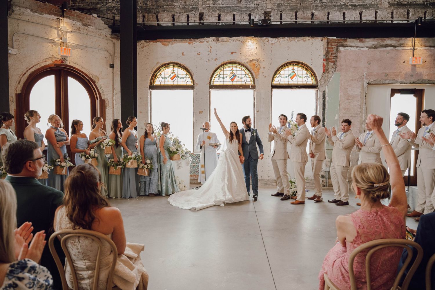 Wedding celebration in an industrial-style venue with exposed brick walls and large windows.