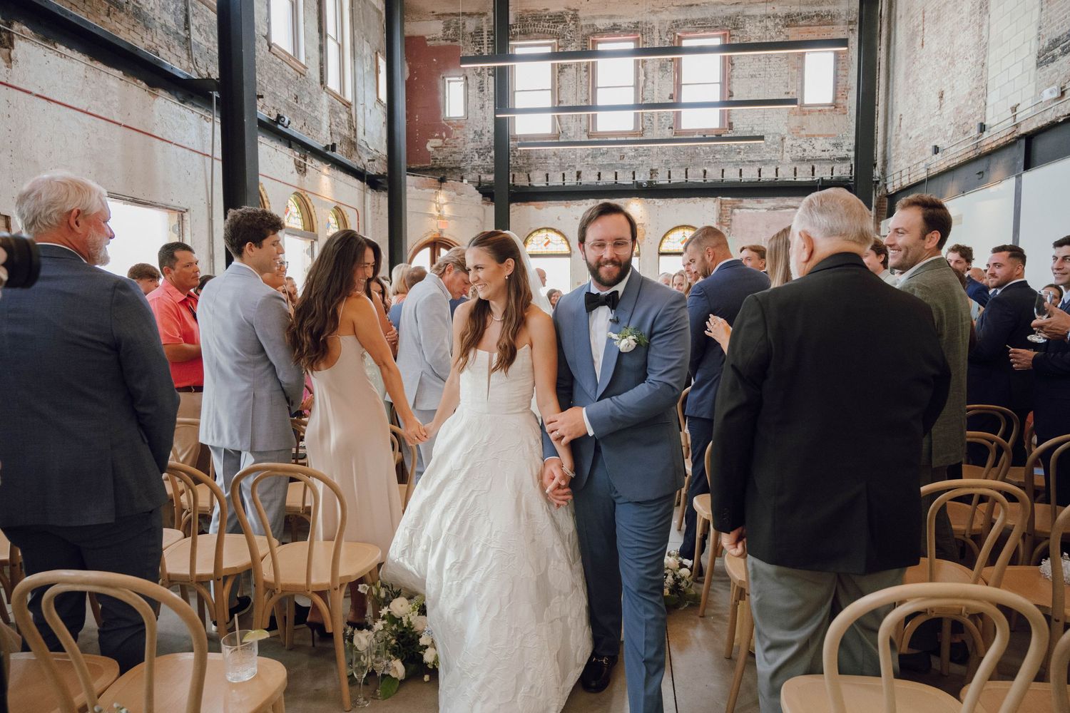 Wedding reception space with rustic wooden chairs and exposed brick architecture.