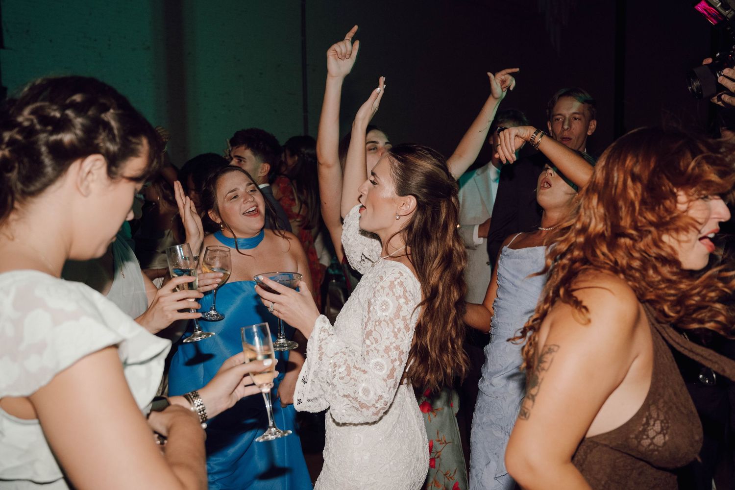 A group of people dancing and socializing at a crowded party or nightclub with dim lighting.