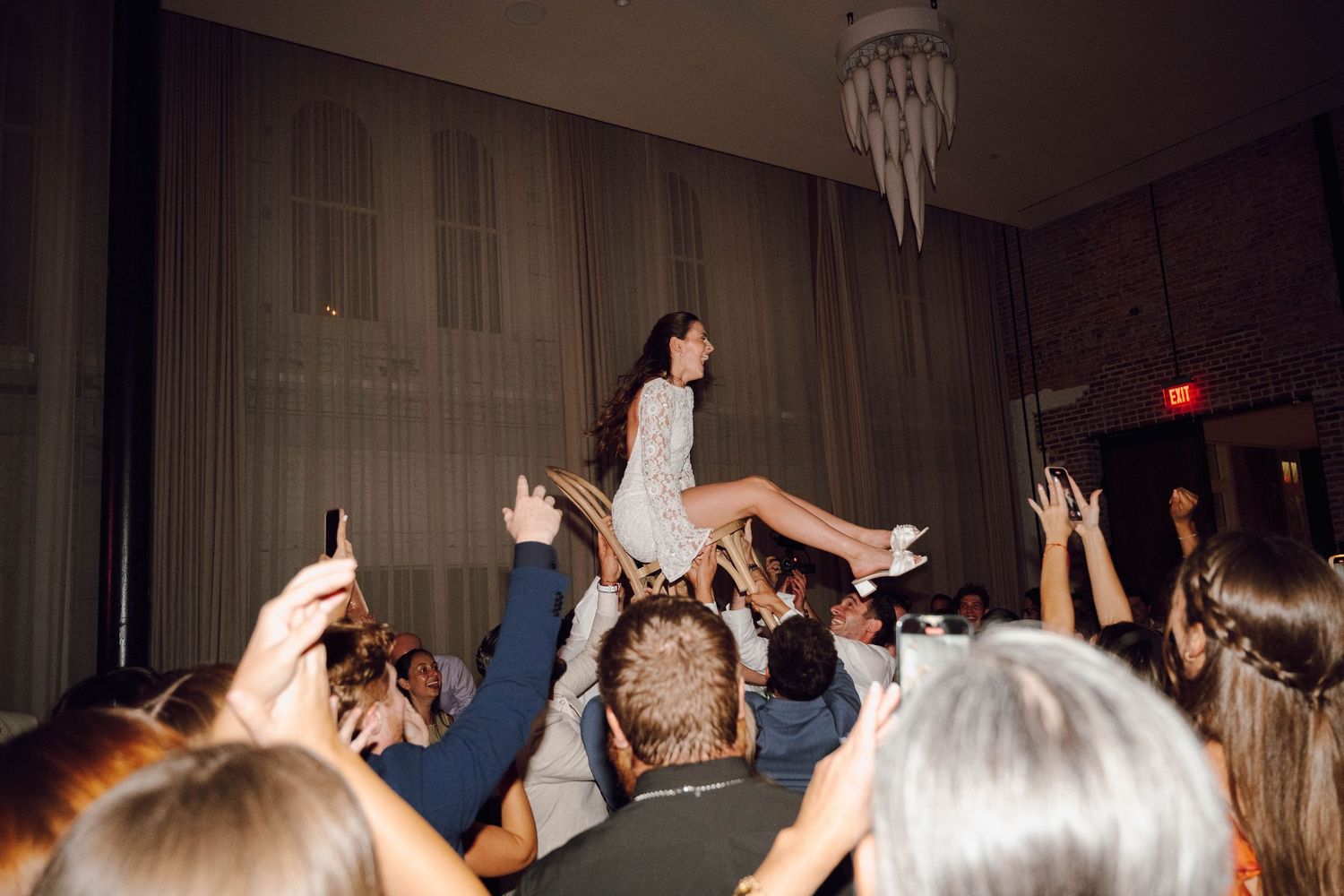 Enthusiastic partygoers with raised arms enjoying themselves at a dimly lit indoor celebration.