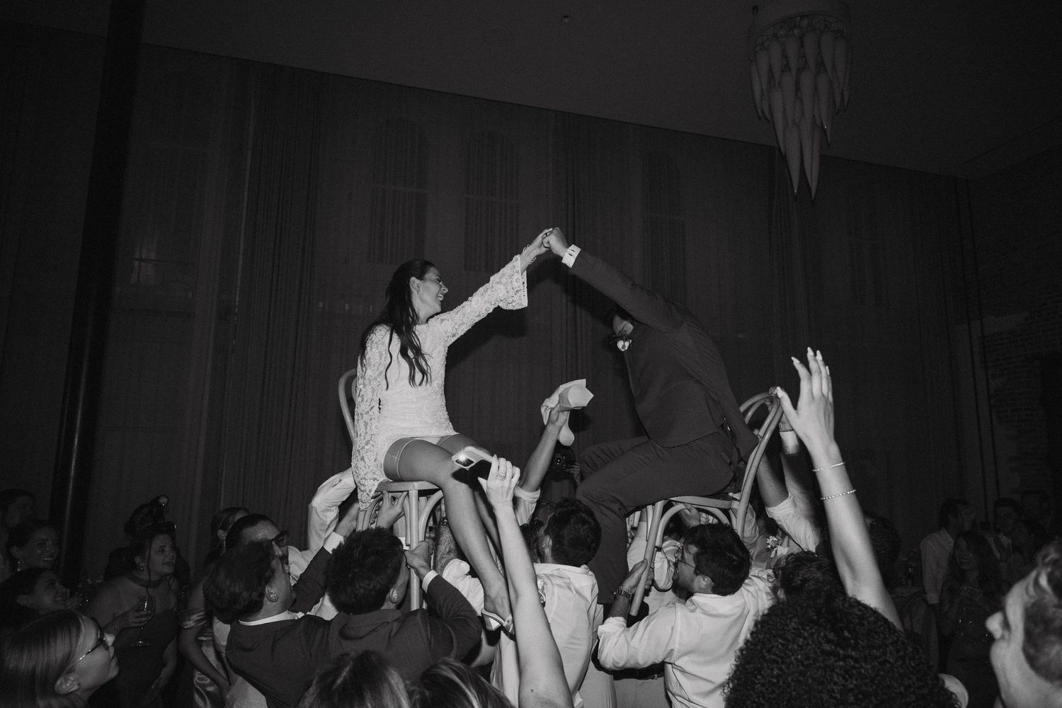 Black and white photo of a crowd dancing with raised hands at what appears to be a concert or nightclub event.