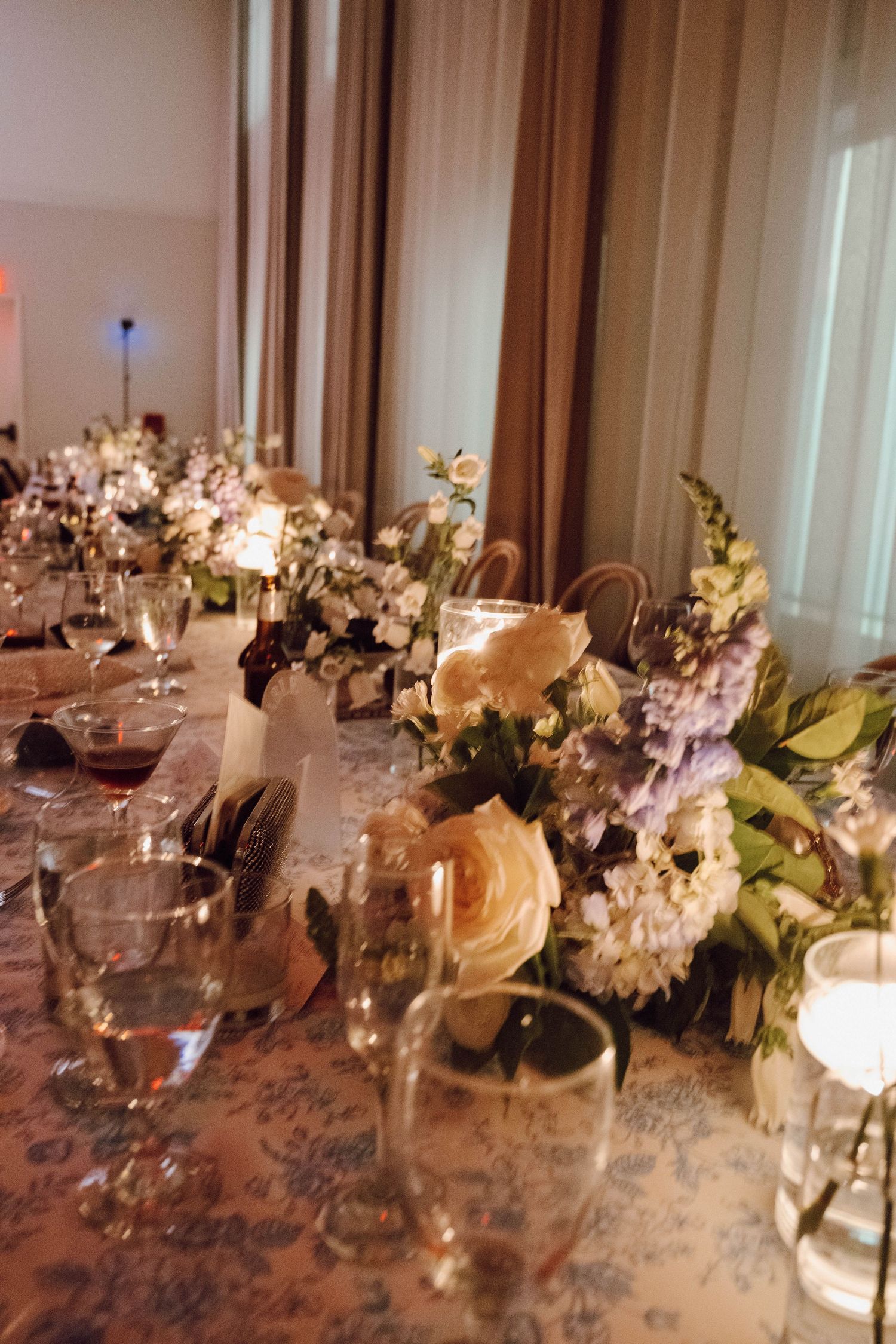Elegant wedding reception table with white floral centerpieces, candles and wine glasses.