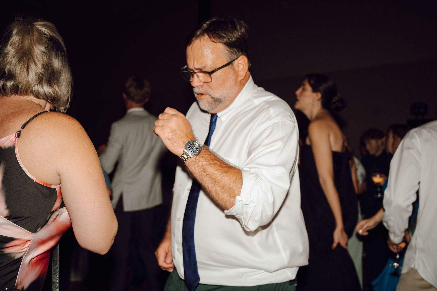 People dance together in a dimly lit room during what appears to be a social dance event or party.