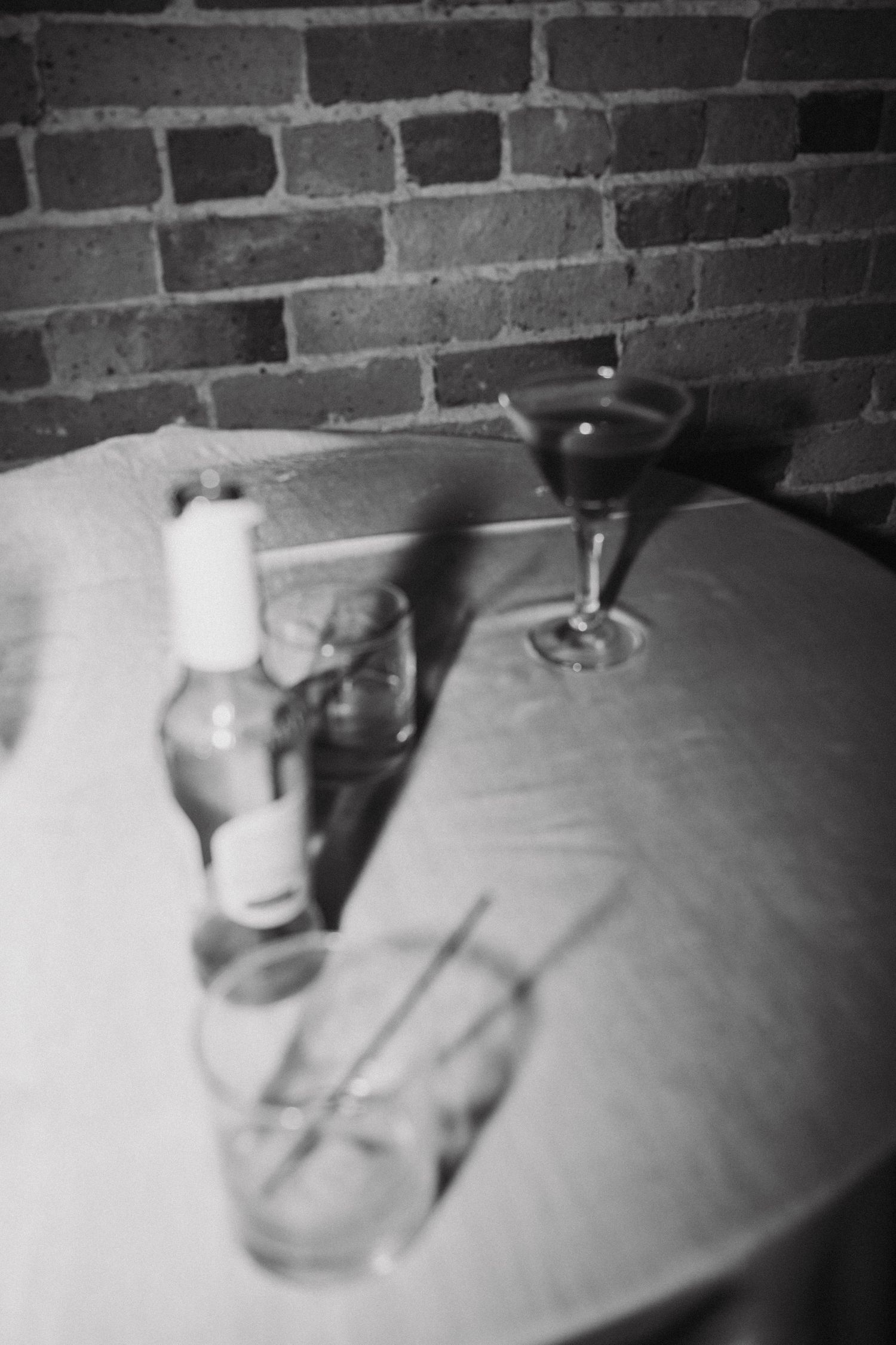 Black and white image showing several small objects casting shadows on a textured surface against a brick wall background.
