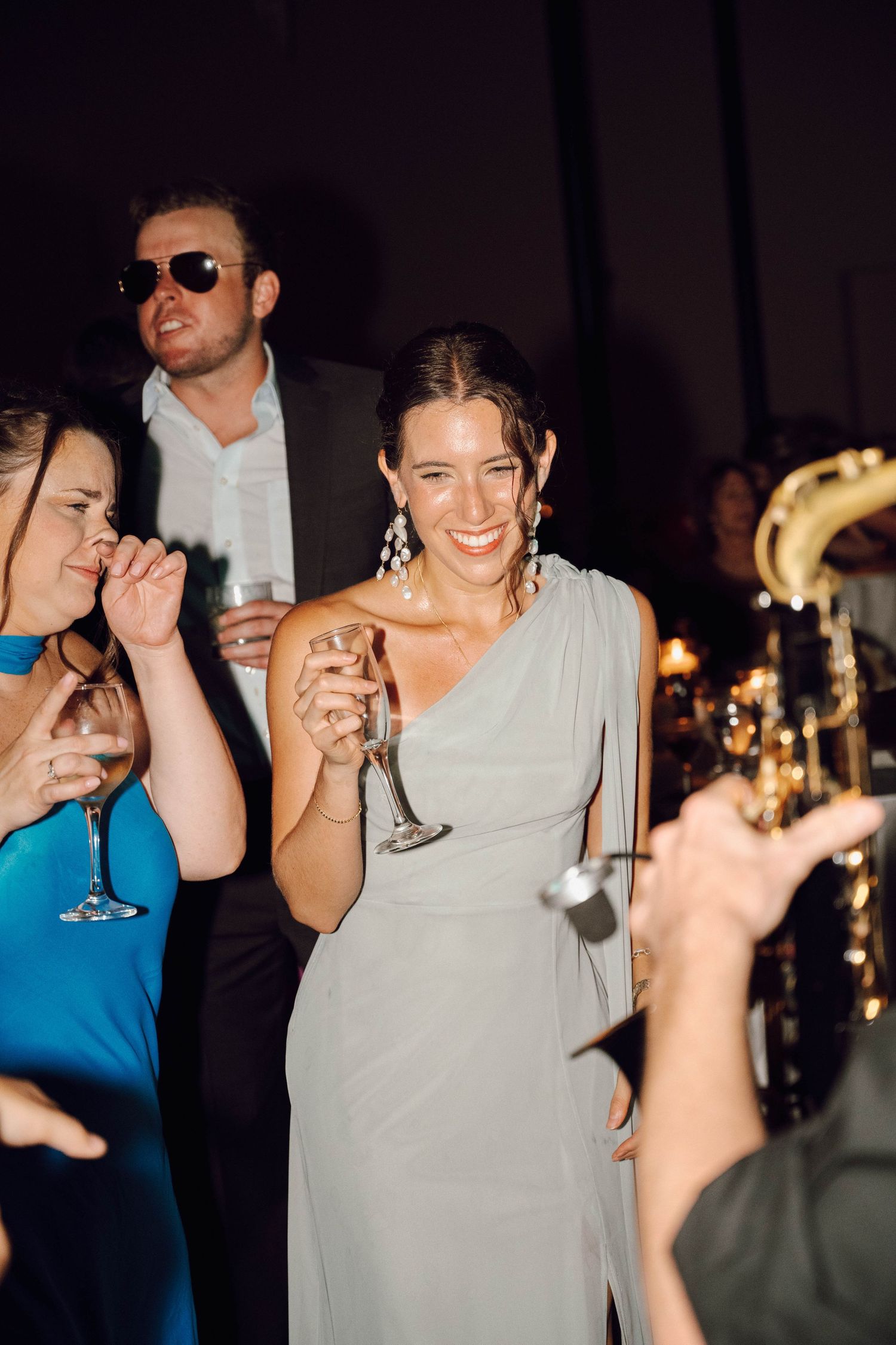 People dancing and celebrating at a dimly lit party with candlelit tables in the background.