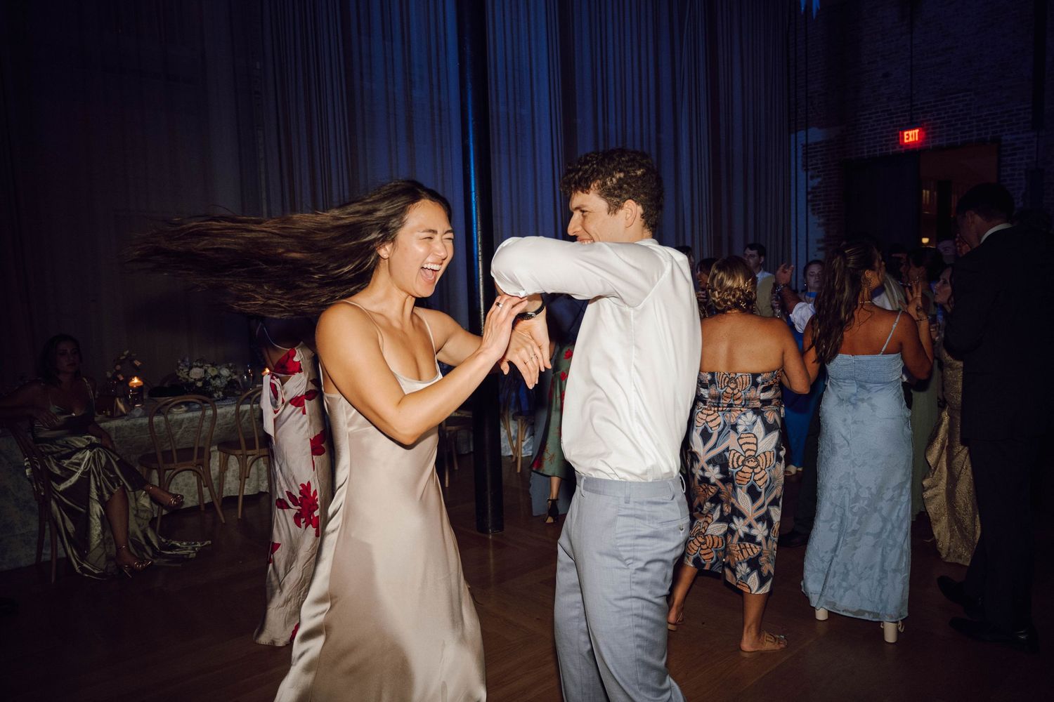 Couples dancing together at a wedding reception in a dark ballroom with decorative lighting.