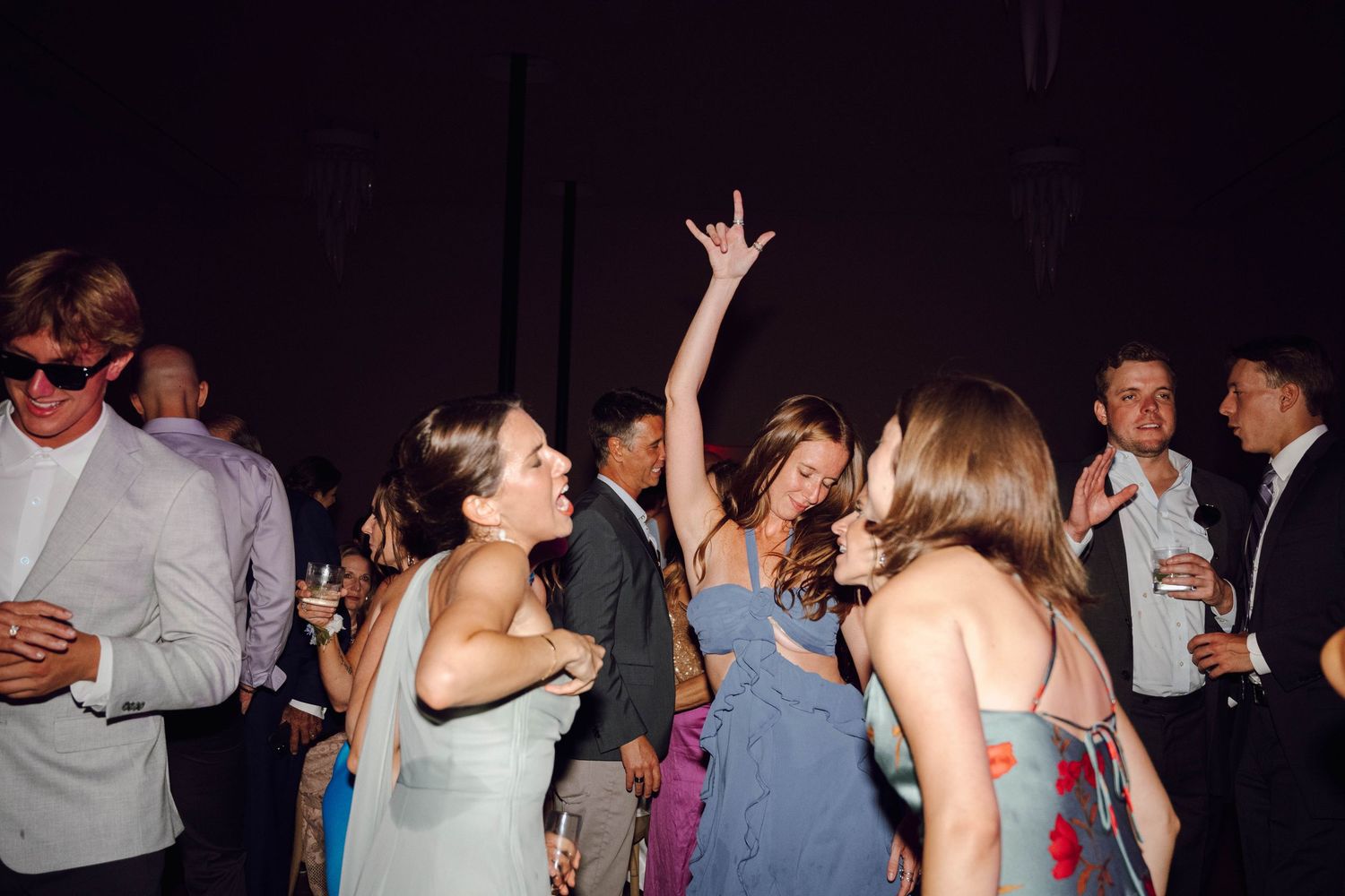 People dancing with raised arms and enjoying themselves at a lively indoor party celebration.