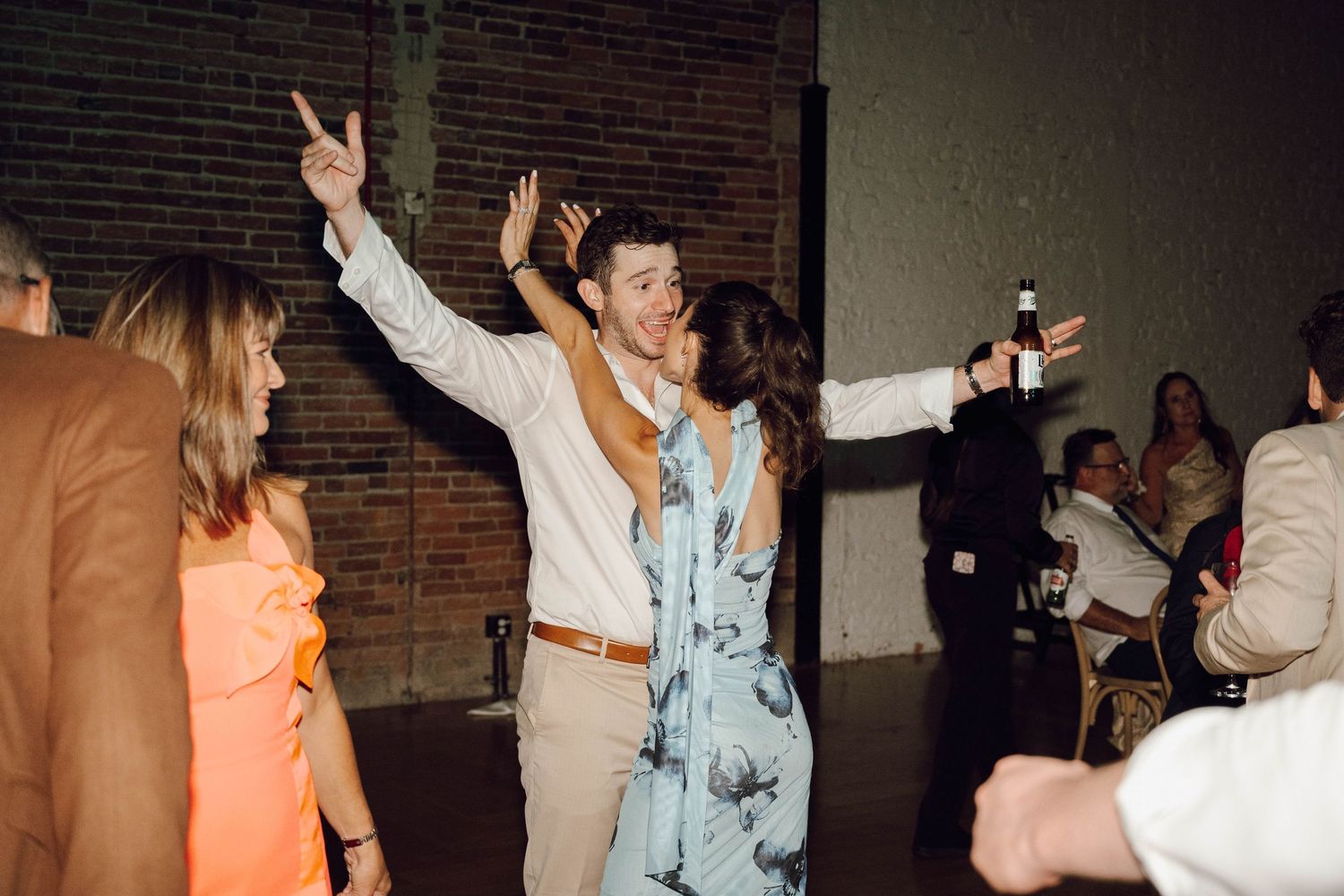 Silhouettes of people dancing and having fun at a dark indoor party venue.