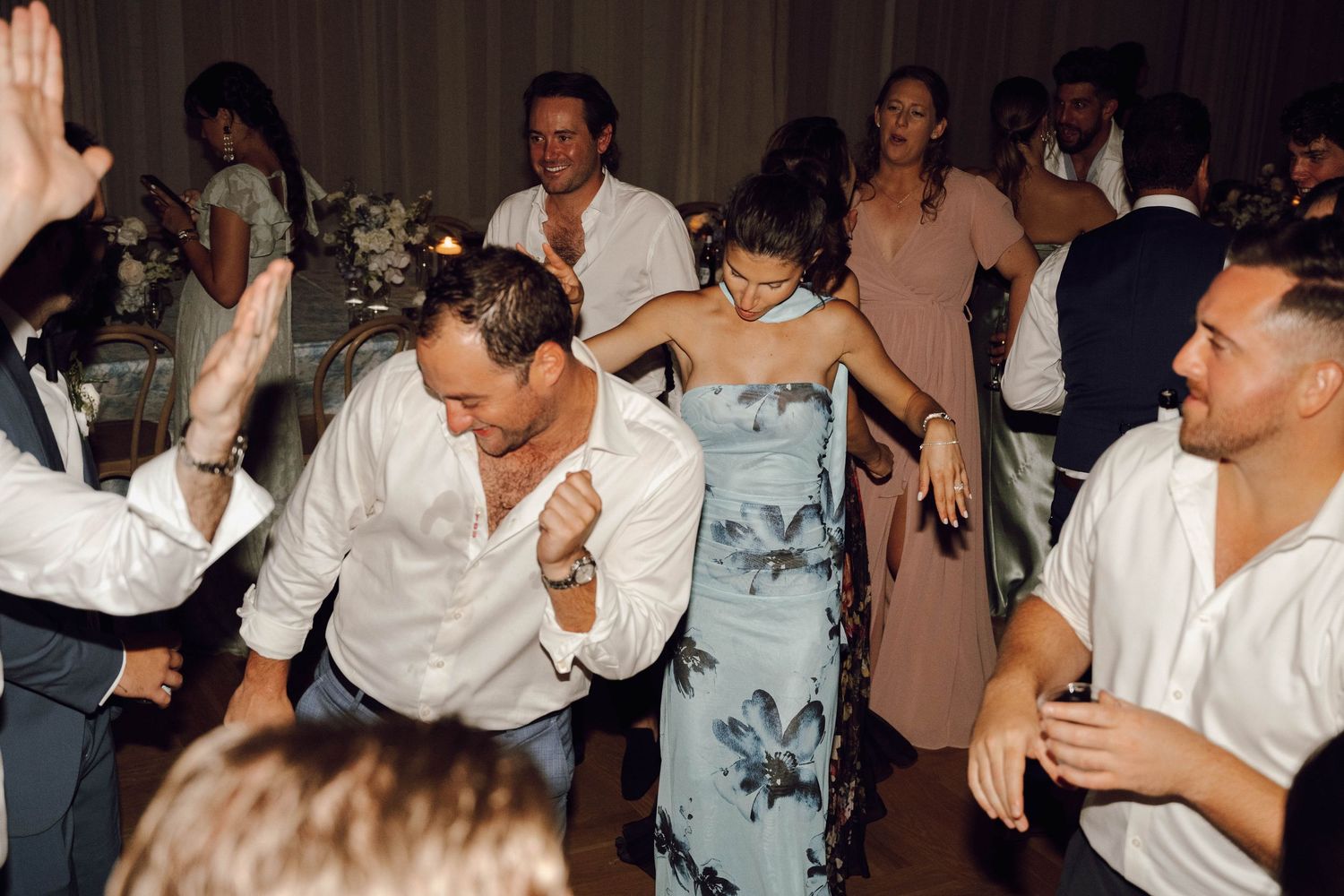 People dancing and celebrating at a lively party or social gathering in a dimly lit venue.