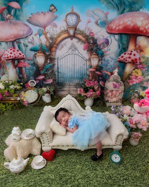 Sleeping newborn baby in blue tutu dress on miniature sofa in Alice in Wonderland themed photo shoot.