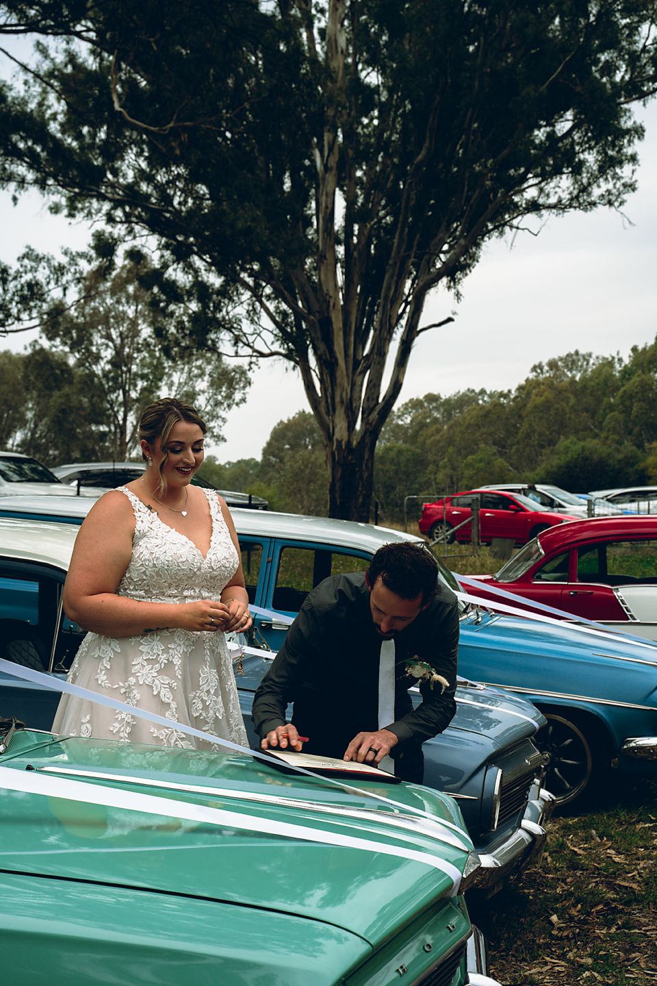 A couple poses with a mint green classic car during what appears to be a wedding photoshoot.