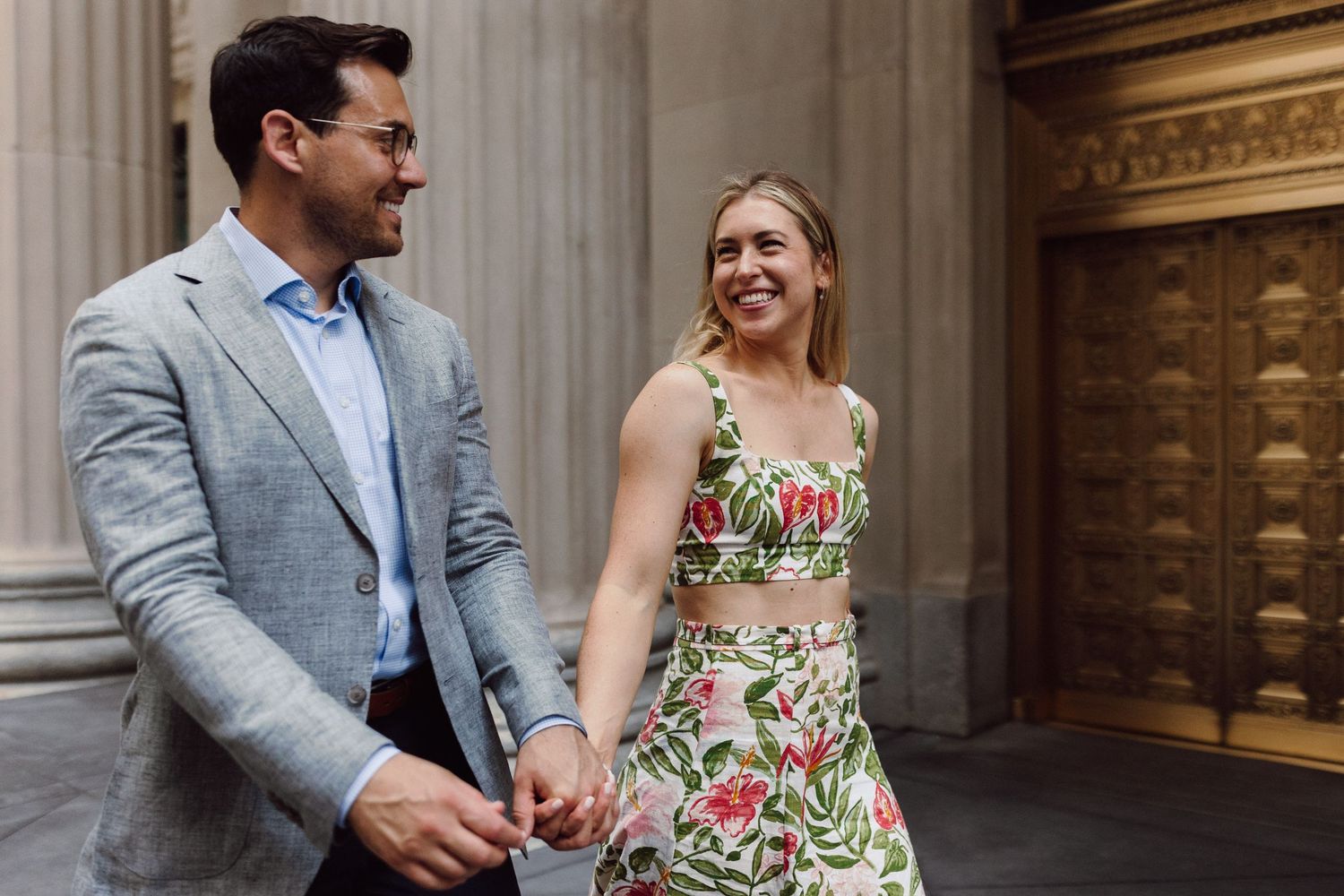 Couple in elegant attire sharing moments near ornate architectural columns.